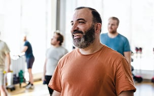 Smiling man looking away with male friends in background at exercise class