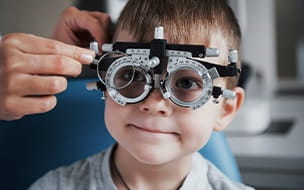 A little boy having testing his eyes in the doctor's office with a phoropter