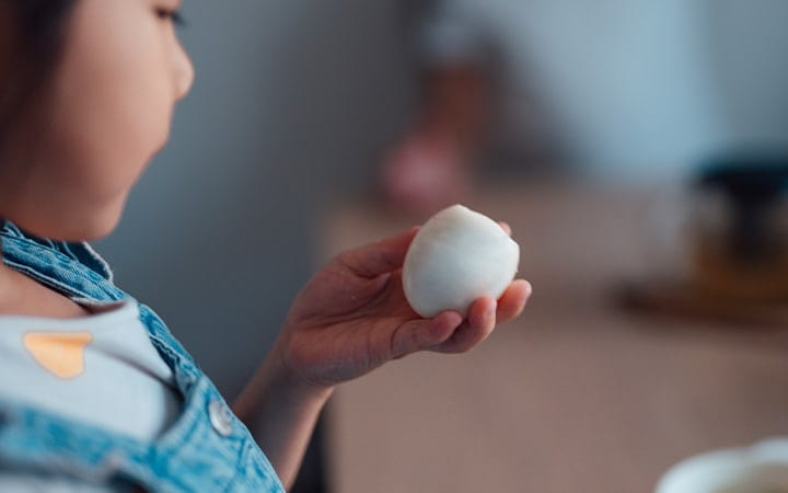 A young girl holds a hard boiled egg in her hand