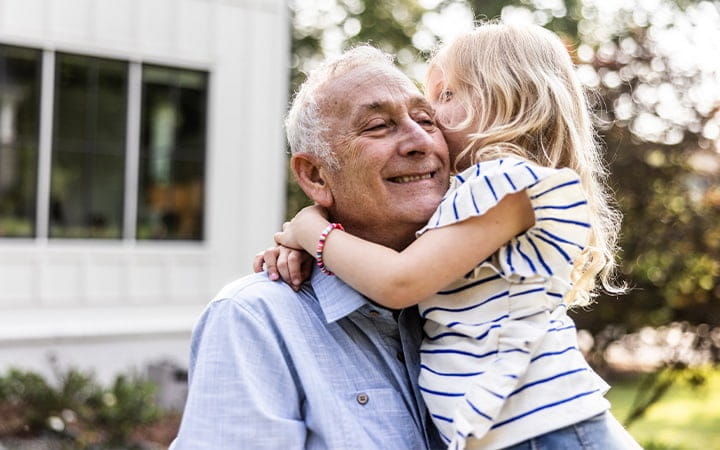 Smiling grandfather hugging granddaughter
