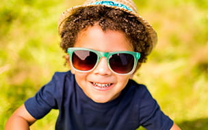 young boy with green sunglasses against yellow background