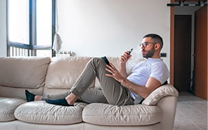 A man smoking while using digital tablet on sofa at home