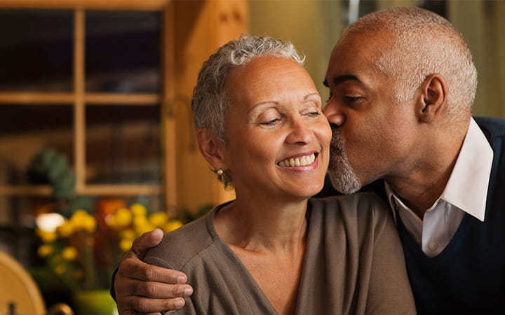 older man kissing cheek of smiling older woman