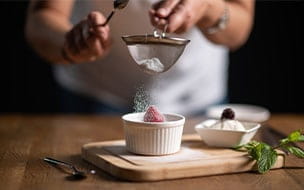 A chef sprinkling powdered sugar on chocolate souffle