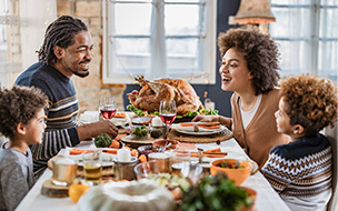 family of four gathered around square thanksgiving table