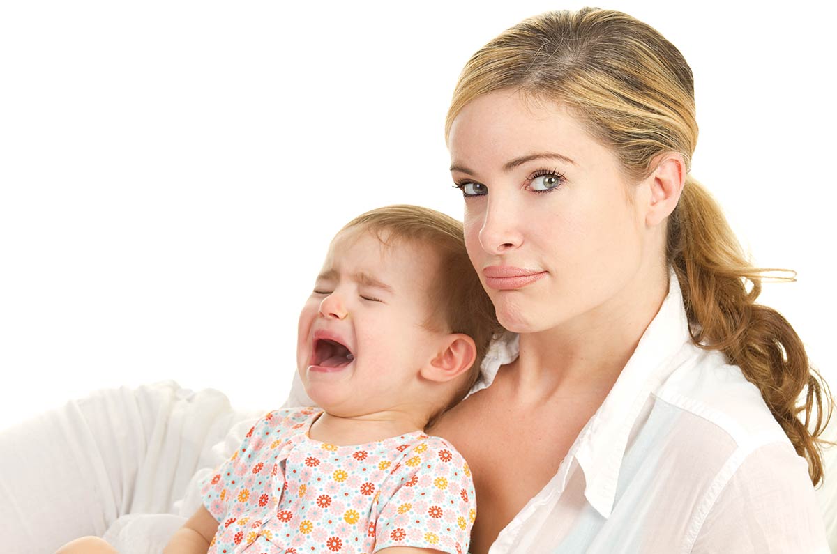 frustrated-looking woman holding a crying toddler