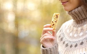 A woman holds a granola bar while enjoying the outdoors