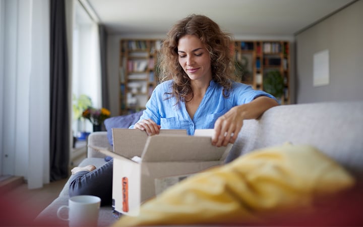 Woman opens delivery box at home