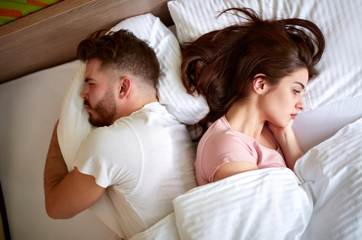 unhappy couple in bed lying back to back