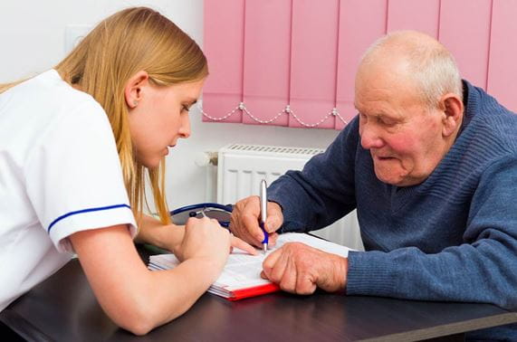 health aide with older man writing