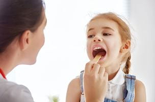 A doctor checking a young girl's tonsils