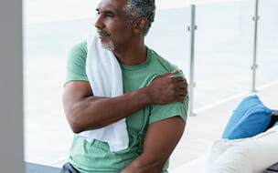 Man holding left shoulder after workout