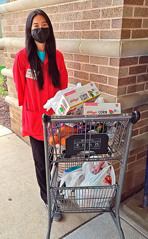 A volunteer at UH Portage Medical Center with a full cart of groceries