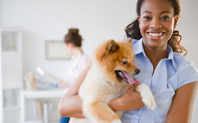 A smiling woman holding a Pomeranian dog