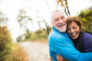 Older couple hugging on wooded path