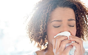 woman holding tissue to her nose with both hands