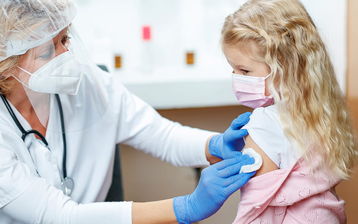Masked physician finishes vaccine with young girl