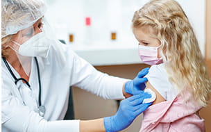 Masked physician finishes vaccine with young girl
