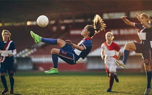 A female soccer player doing the bicycle kick on a soccer match at a stadium
