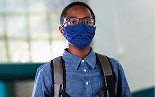 young boy wearing backpack and mask
