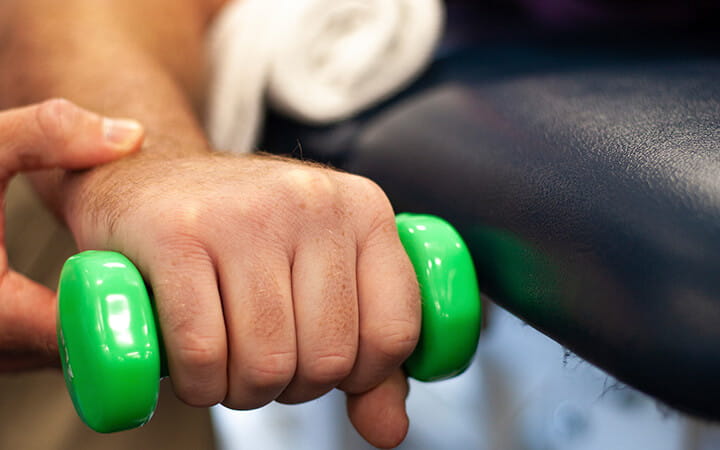 Man exercising wrist with dumbbell