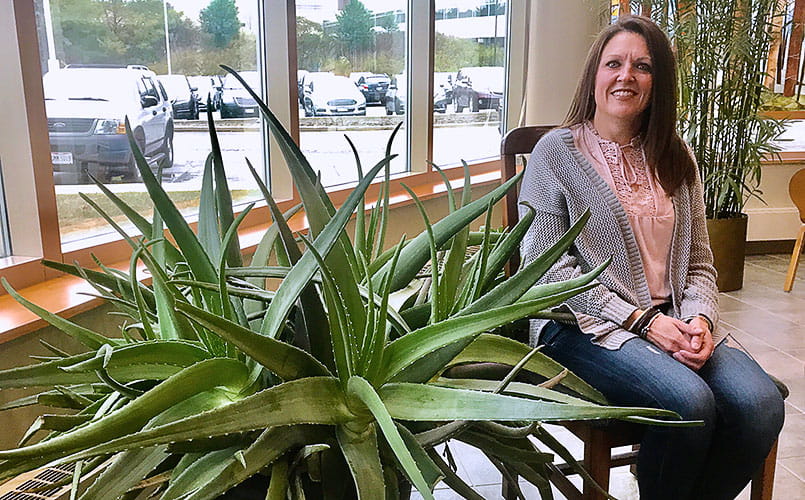 Carrie Boyert sits beside an aloe plant in the lobby of UH Seidman Cancer Center
