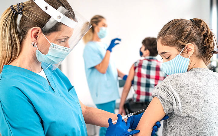 Female doctor injecting COVID-19 vaccine into young patient's arm