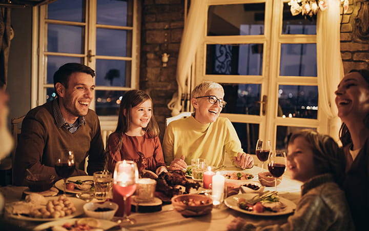 multigenerational family gathered around candlelit table laughing