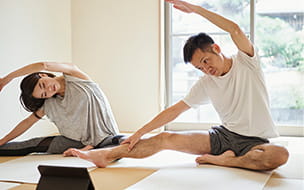man and woman doing seated side stretches at home