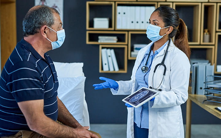doctor with gloves and mask talking with male patient with mask