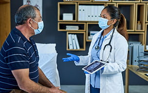 doctor with gloves and mask talking with male patient with mask