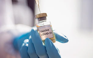 gloved hand holding covid vaccine vial