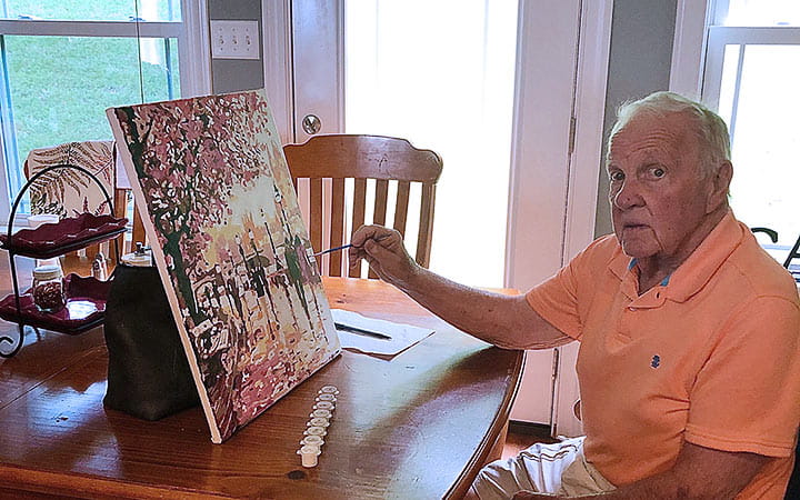 Walter Carson paints in his dining room.