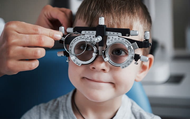A little boy having testing his eyes in the doctor's office with a phoropter