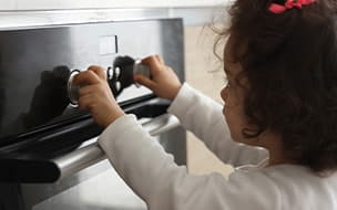A little girl turns knobs on an oven