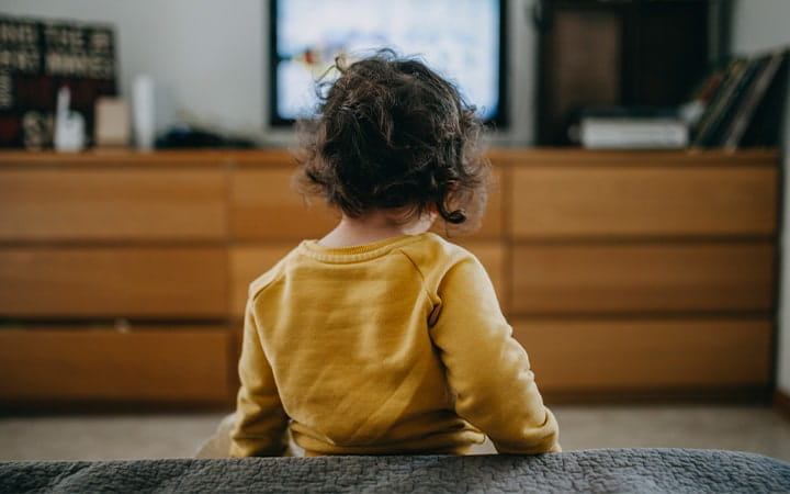 A young girl watches TV at home
