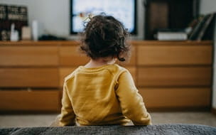 A young girl watches TV at home