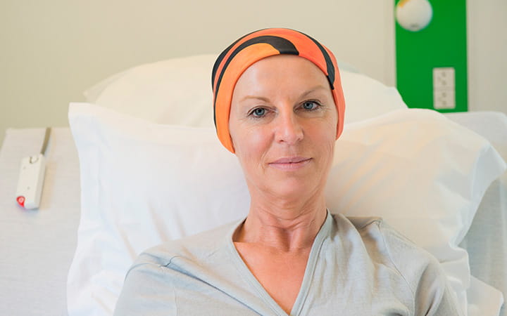 female cancer patient in hospital bed wearing head wrap