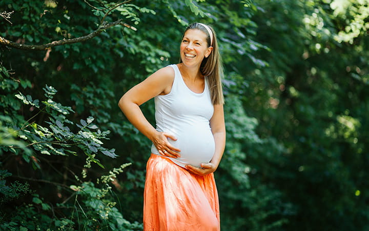 pregnant woman in woods wearing tank top and skirt