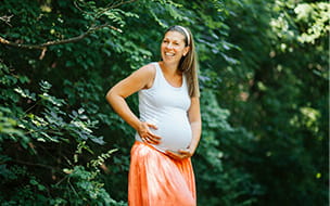 pregnant woman in woods wearing tank top and skirt