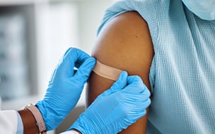 A doctor applying a sticking plaster to her patient's arm