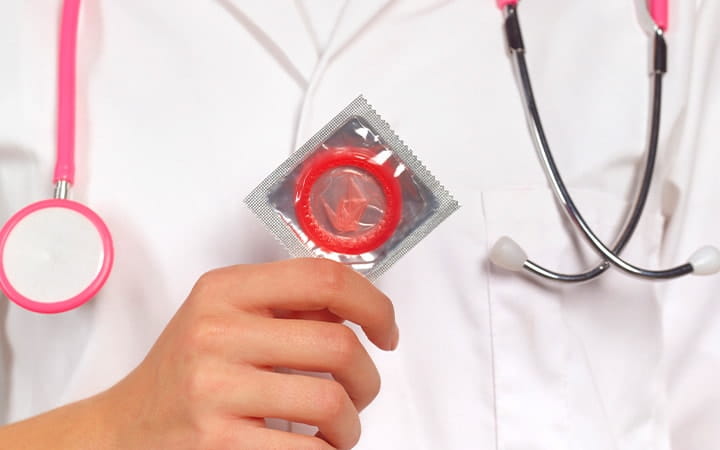 A close-up of a doctor holding a condom