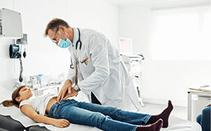 Male pediatrician pressing stomach of girl during checkup