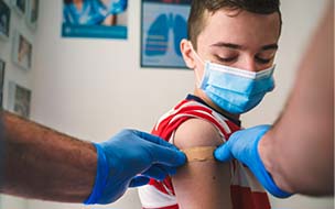 young boy getting an adhesive bandage after a shot
