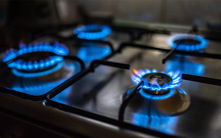 Closeup view of the four lit hobs of a gas stove