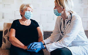 doctor clasps hands with seated female patient