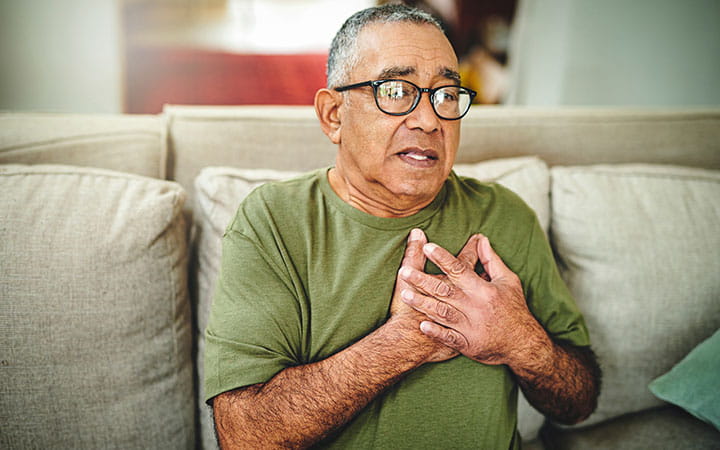 A senior man holding his chest in pain