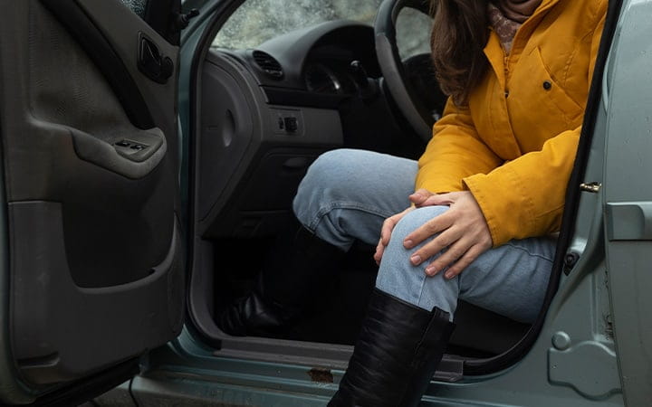A woman experiences pain in her knee when she gets out of her car