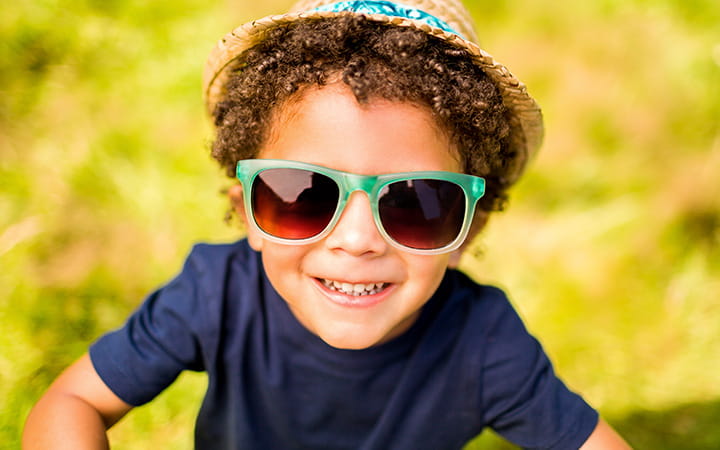 young boy with green sunglasses against yellow background