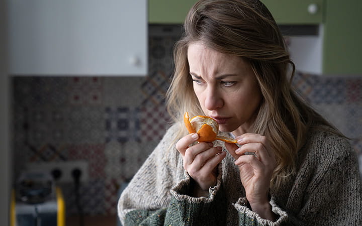 woman smelling peeled orange